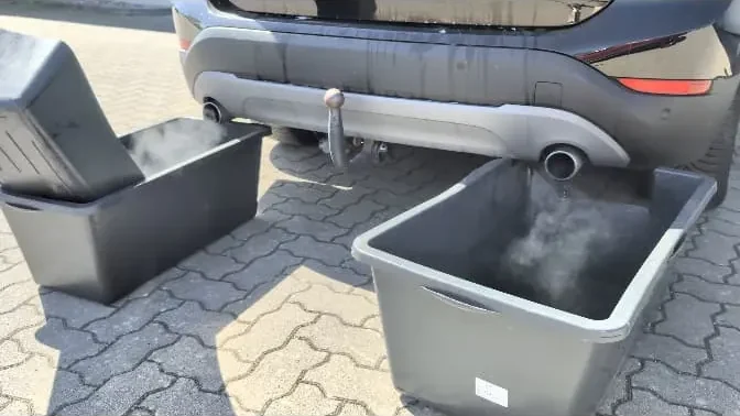 Heckansicht eines SUV, unter den Auspuffrohren fangen zwei Wannen den austretenden Abgasnebel auf