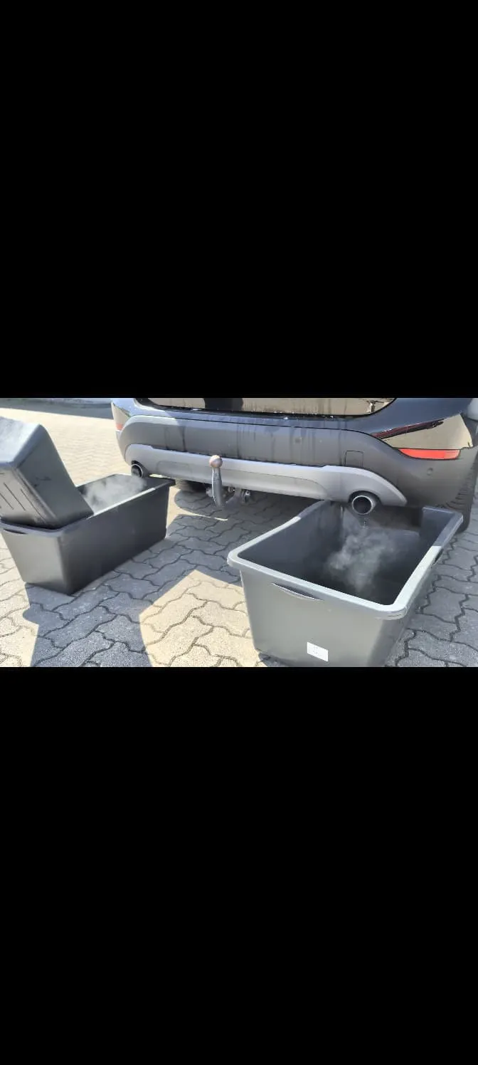 Heckansicht eines SUV, unter den Auspuffrohren fangen zwei Wannen den austretenden Abgasnebel auf