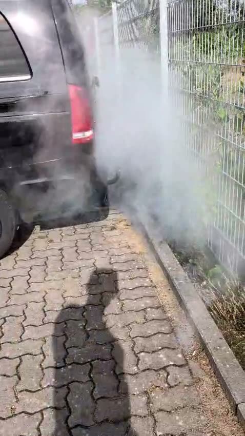 Schwarzer Mercedes Transporter auf dem Hof, aus dem Auspuff tritt dichter heller Reinigungsnebel aus